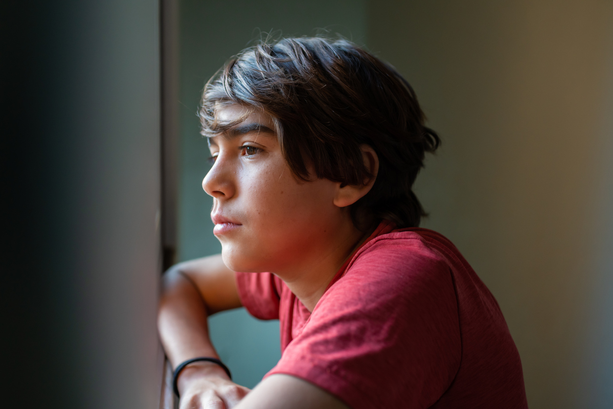 teen boy looking out window