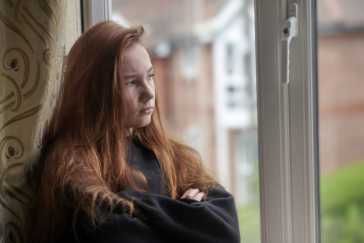 sad teen girl looking out window wondering how common is depression in teens?