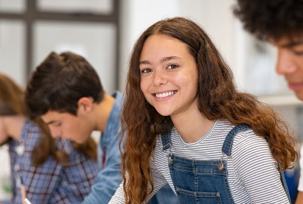 teen girl smiling in classroom after parents asked "what is a therapeutic day school?" and pursued admission