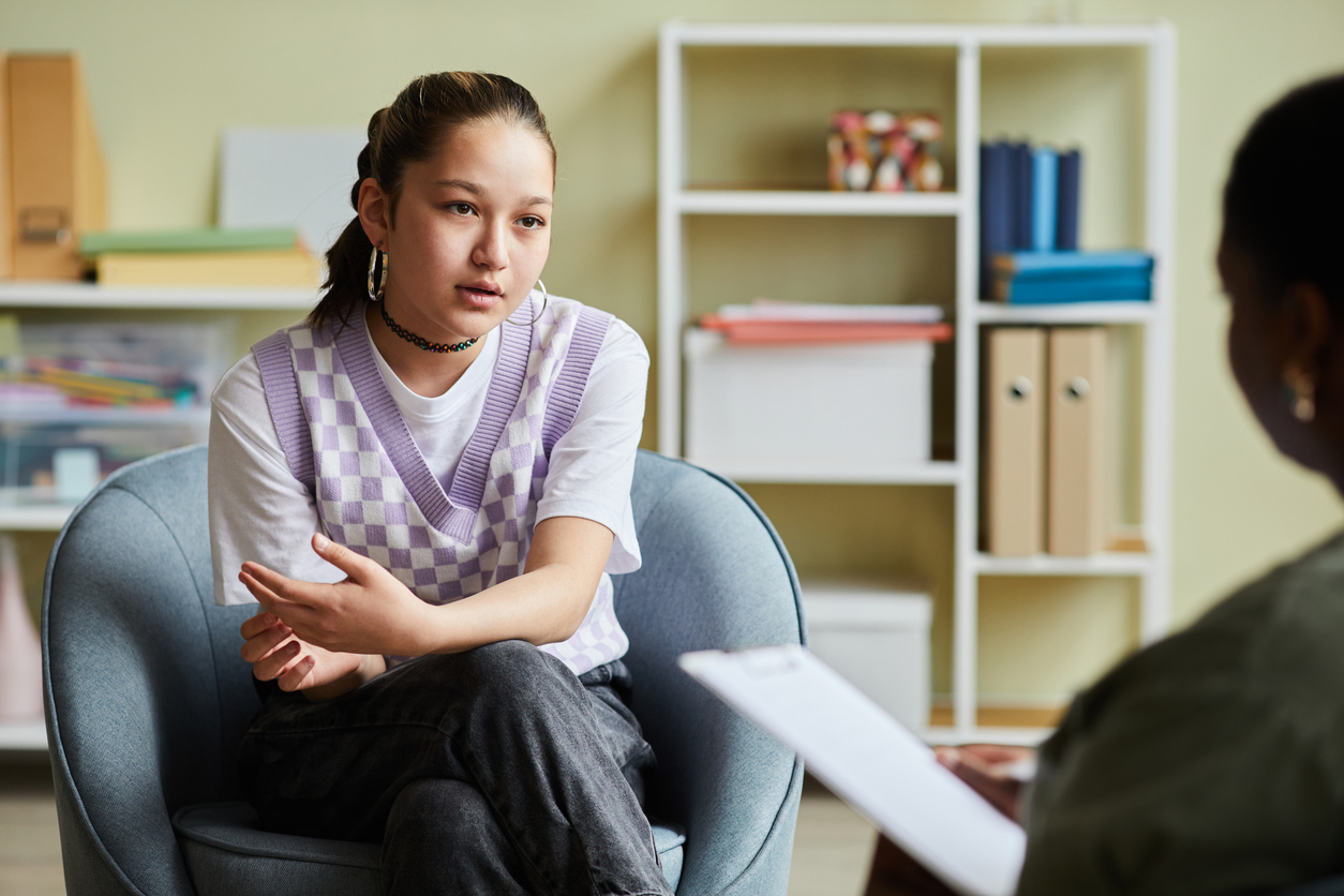teenage girl talking to counselor during teen PTSD and addiction treatment session