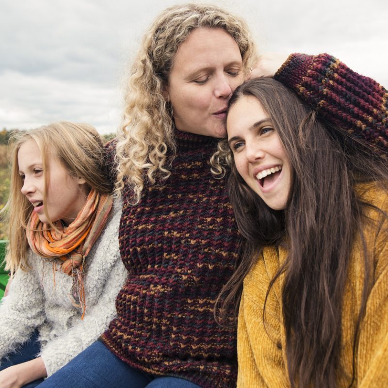 Mother comforting her teenage daughters while talking about teen drug use