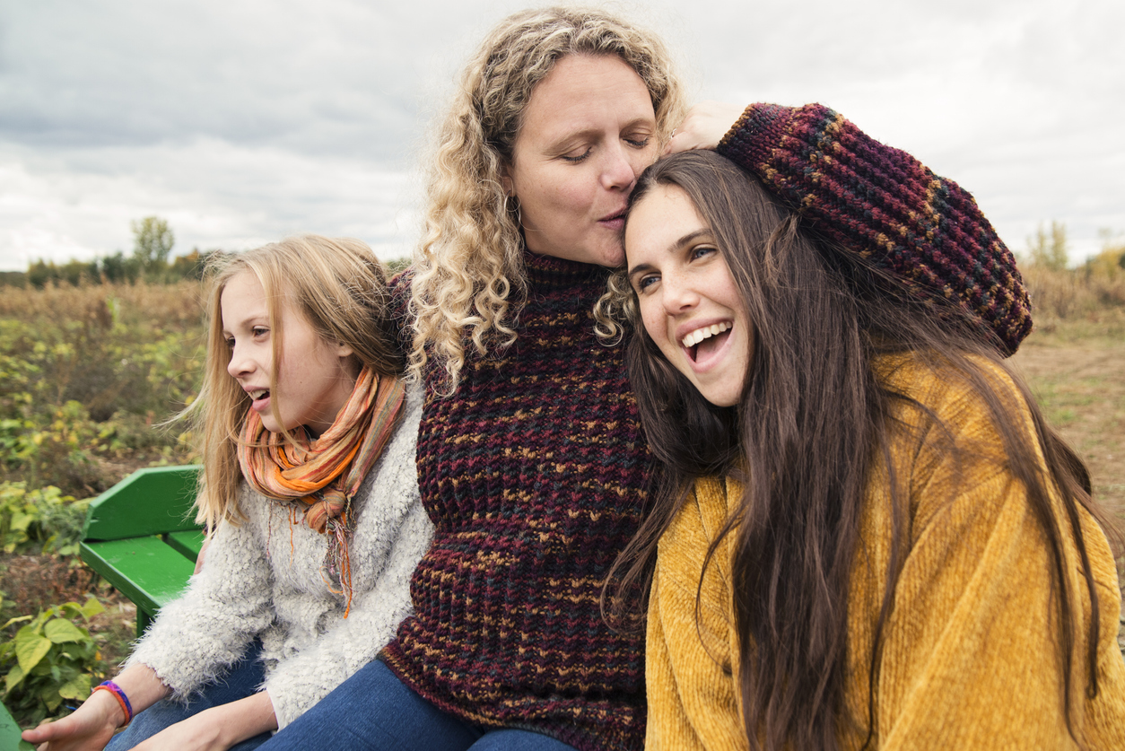 Mother comforting her teenage daughters while talking about teen drug use