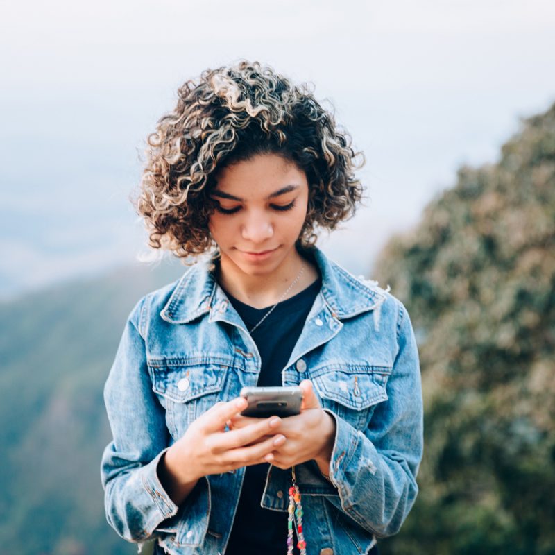 teenage girl using phone to view social media, unaware of the pros and cons of social media for teens